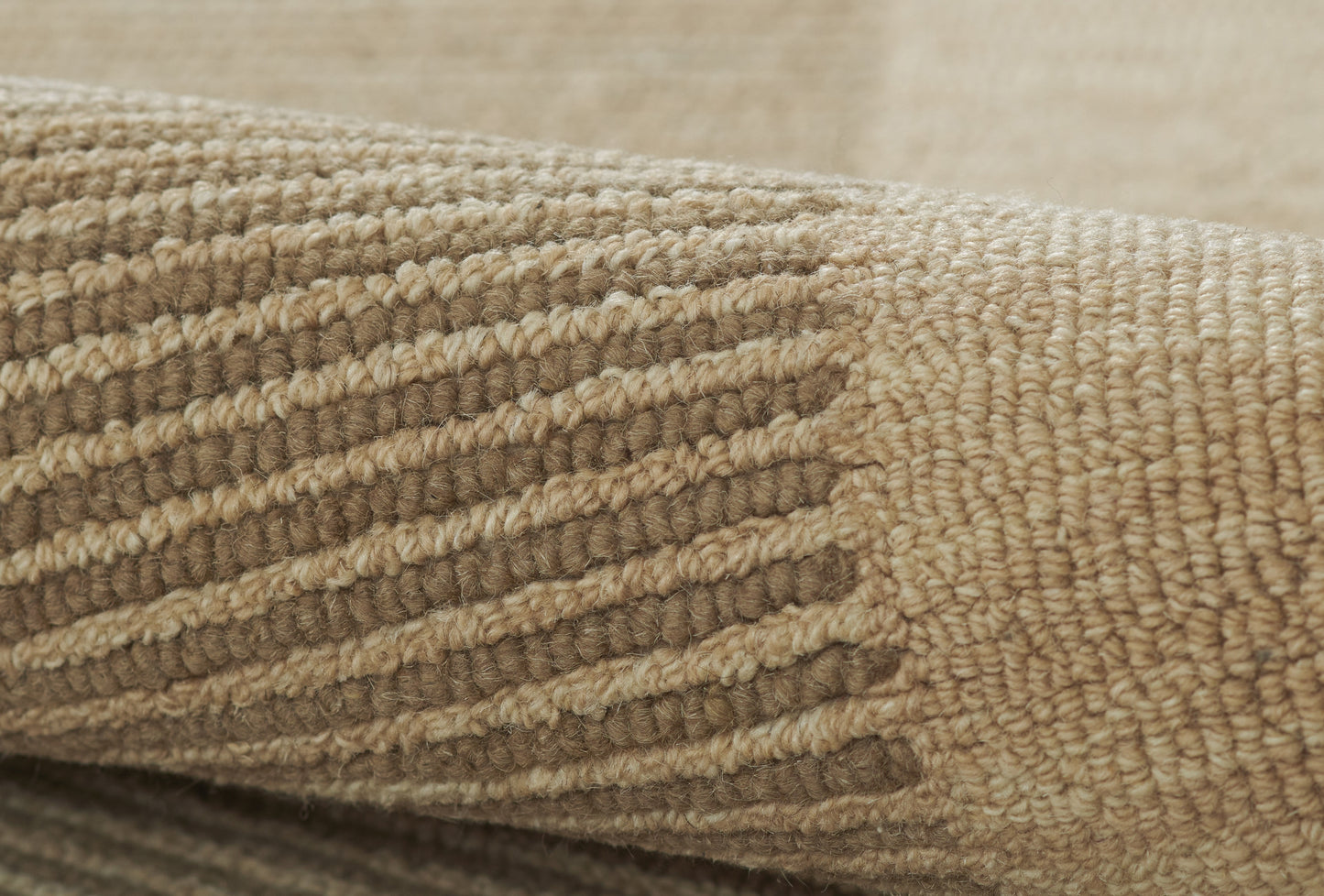 Beige textured woven rug close-up with raised loop stripes and soft wool-like fibers.
