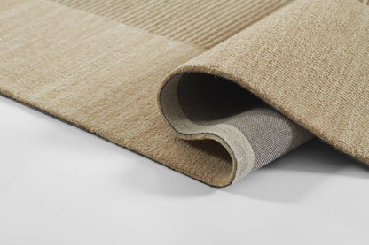 Beige plush area rug with soft fibers; rolled corner reveals grey underside.