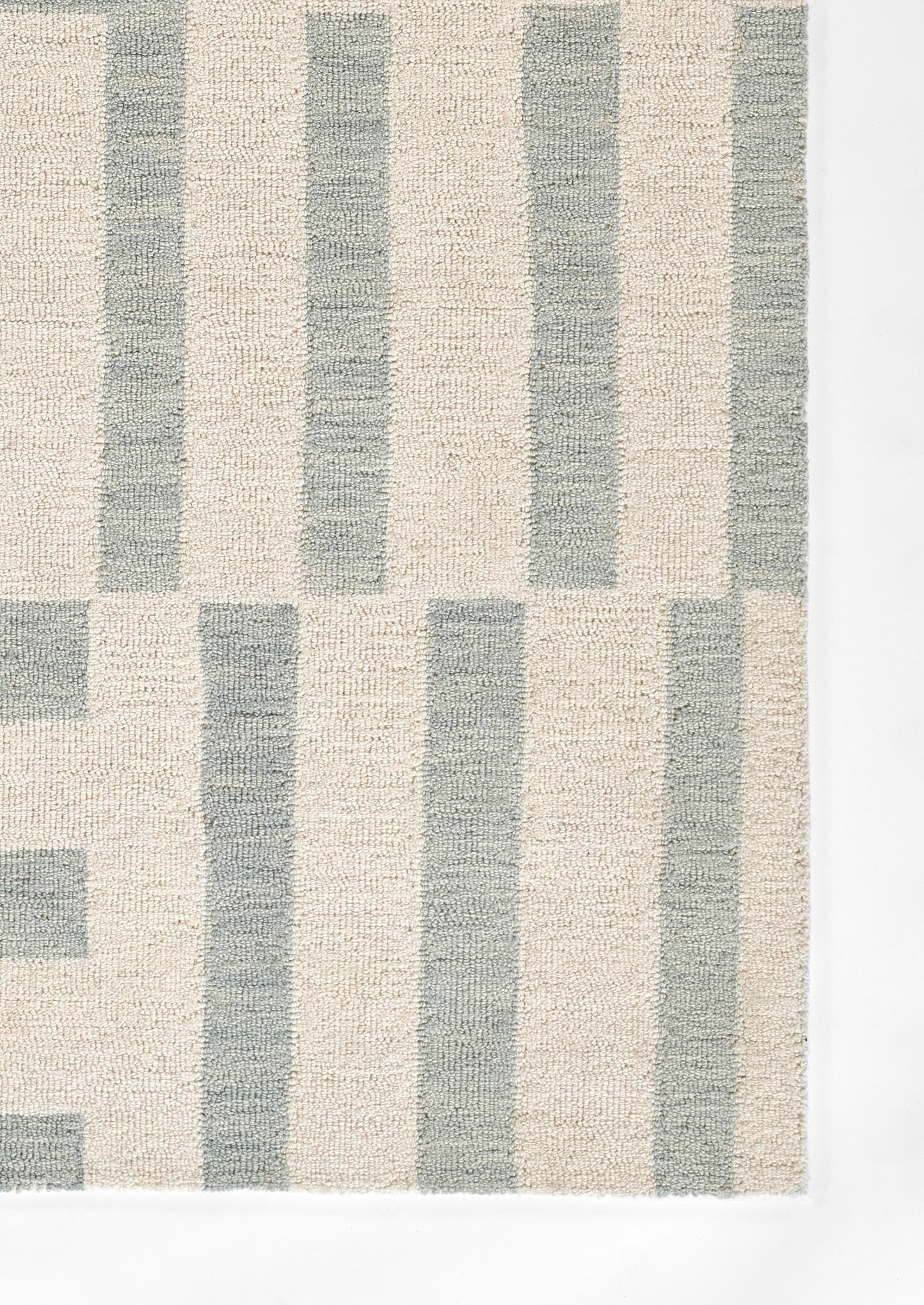 Soft textured beige and blue-gray striped area rug with tall vertical blocks in a geometric pattern.