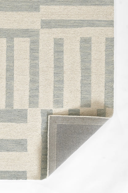 Geometric area rug in cream and blue-gray with rectangular stripe pattern; woven texture, folded corner reveals gray backing.