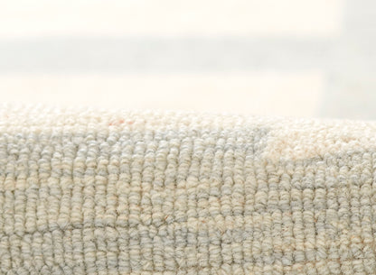 Close-up of neutral beige & blue-gray textured boucle rug; chunky loop weave & plush feel.