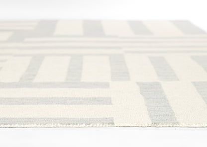 Cream and pale blue geometric rug with rectangular blocks, flat-weave texture, edge visible.
