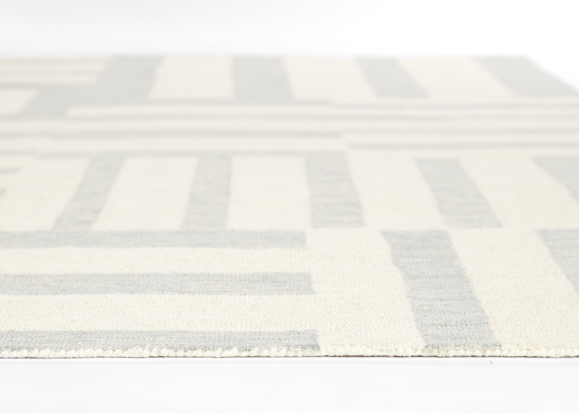 Cream and blue geometric area rug with rectangular bar pattern and fringe along the edge.