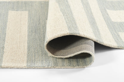 Blue and ivory geometric area rug with soft, woven texture; folded corner reveals gray backing.