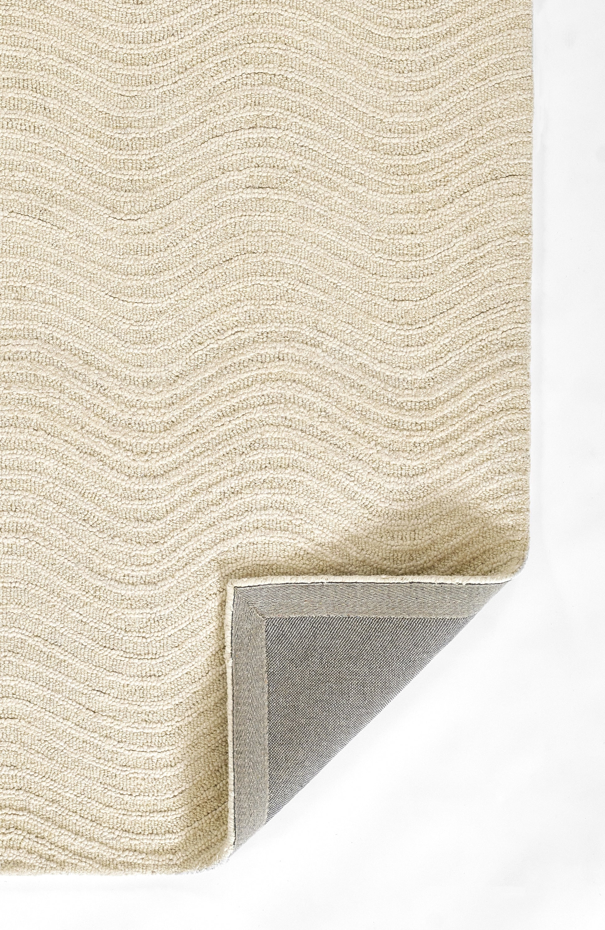 Beige textured rug with a wavy loop pattern; folded corner reveals gray underside and binding, modern cozy area rug.