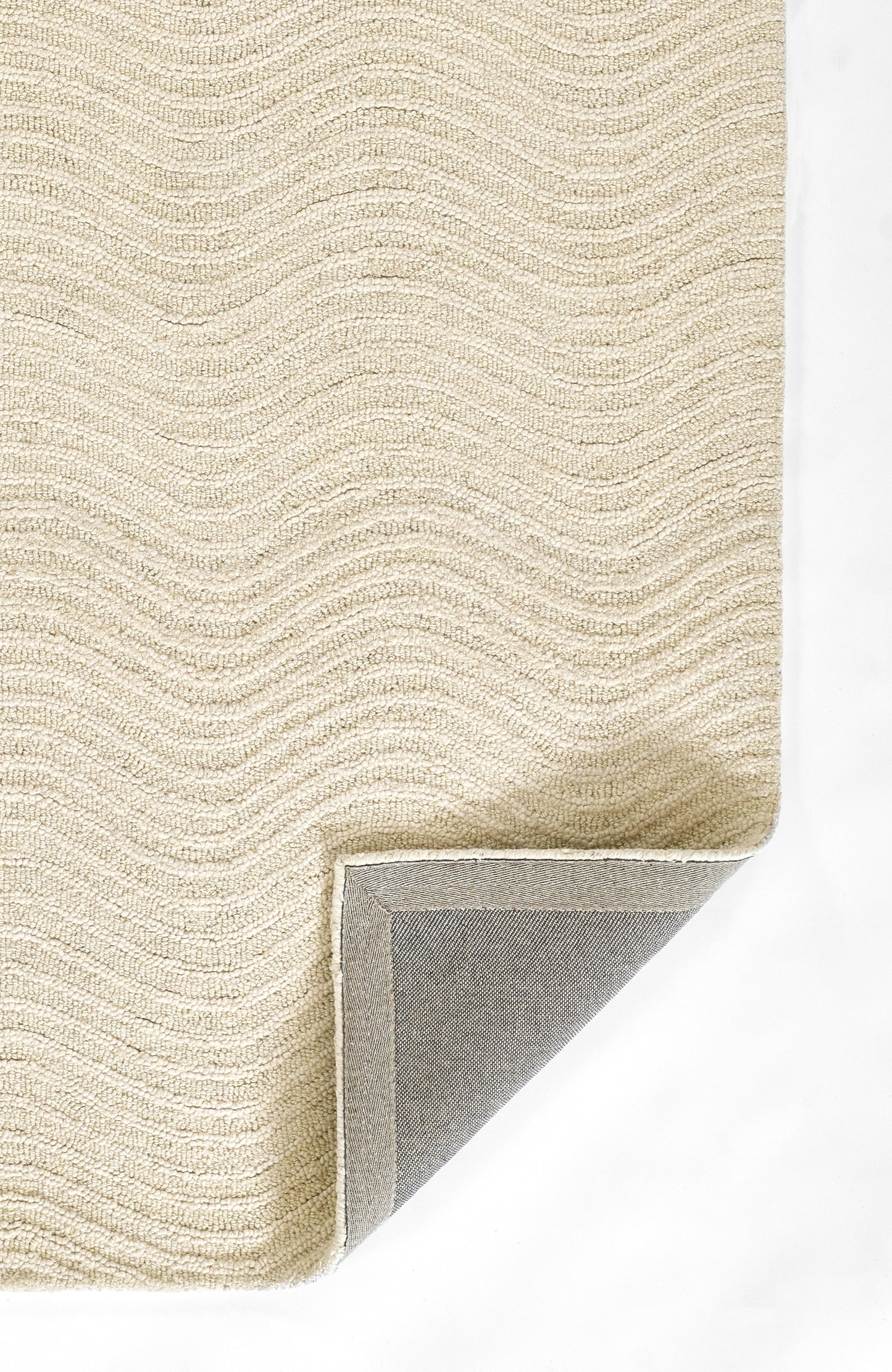 Beige textured loop-pile rug with subtle wave pattern; folded corner shows grey backing.