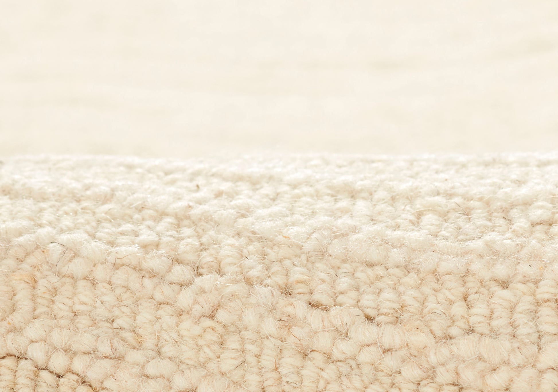 Cream wool looped-pile rug close-up; soft textured beige carpet for living areas.