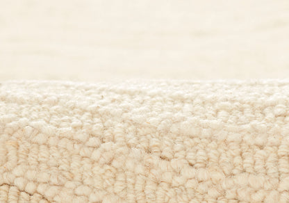 Close-up of beige looped-pile carpet fibers with a soft, fluffy texture for a cozy area rug.