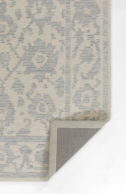 Beige rug with pale blue damask pattern; rectangular, folded corner reveals gray non-slip backing.