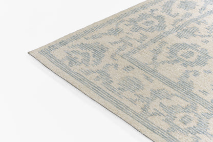 Beige rug with light blue damask pattern, rectangular decorative rug, corner view.