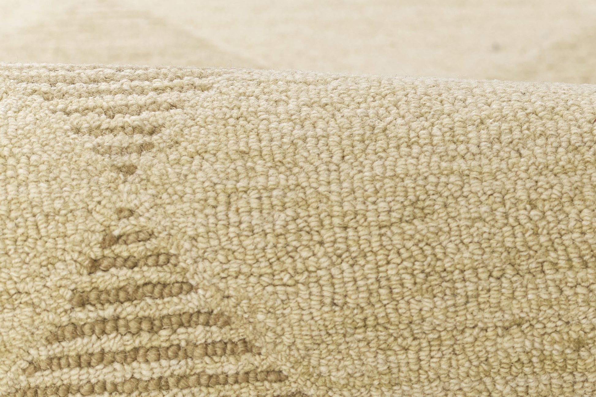 Beige textured rug close-up with loop pile and subtle geometric stepped pattern.