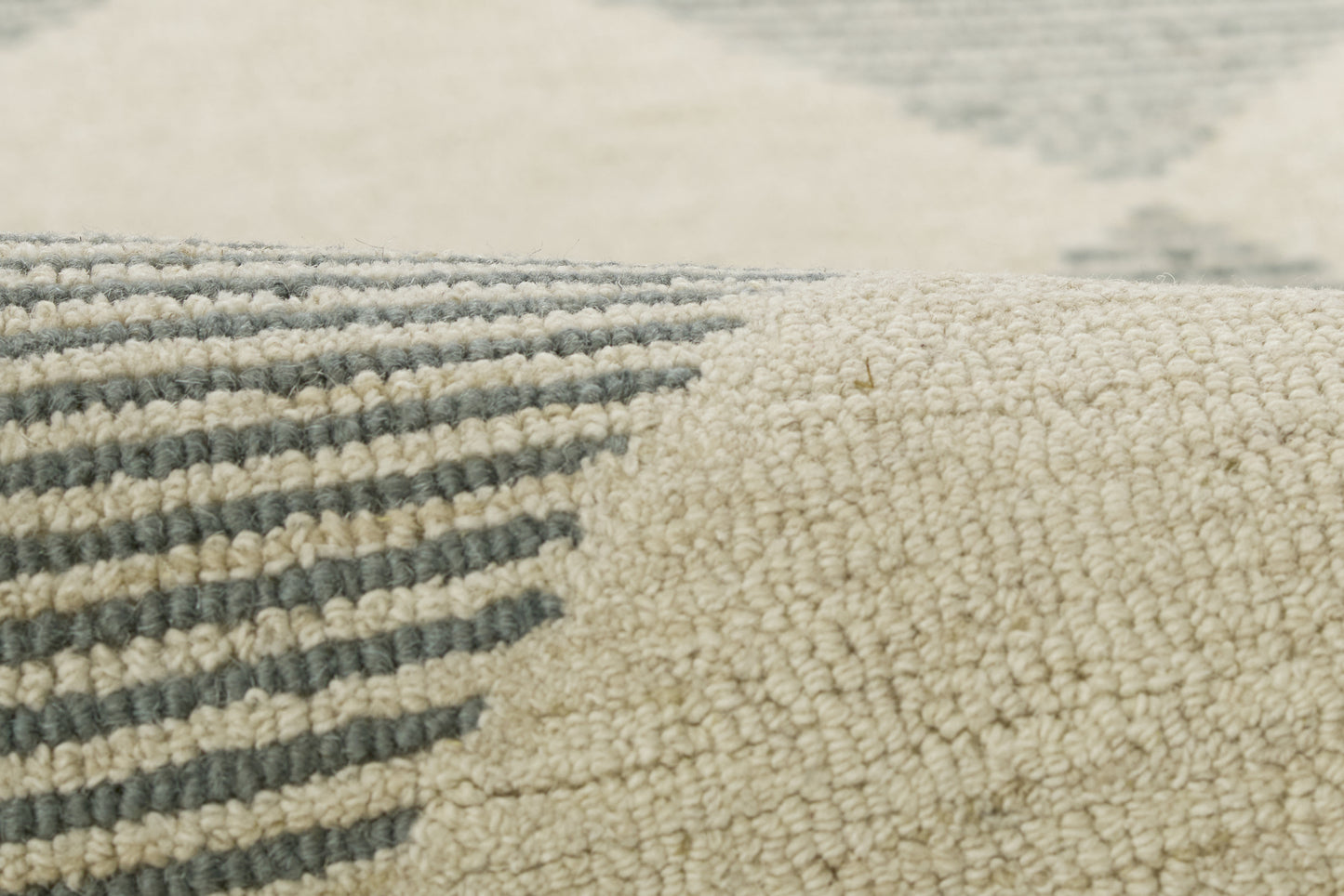 Close-up of a cream and blue-gray geometric rug with striped pattern and soft looped pile.