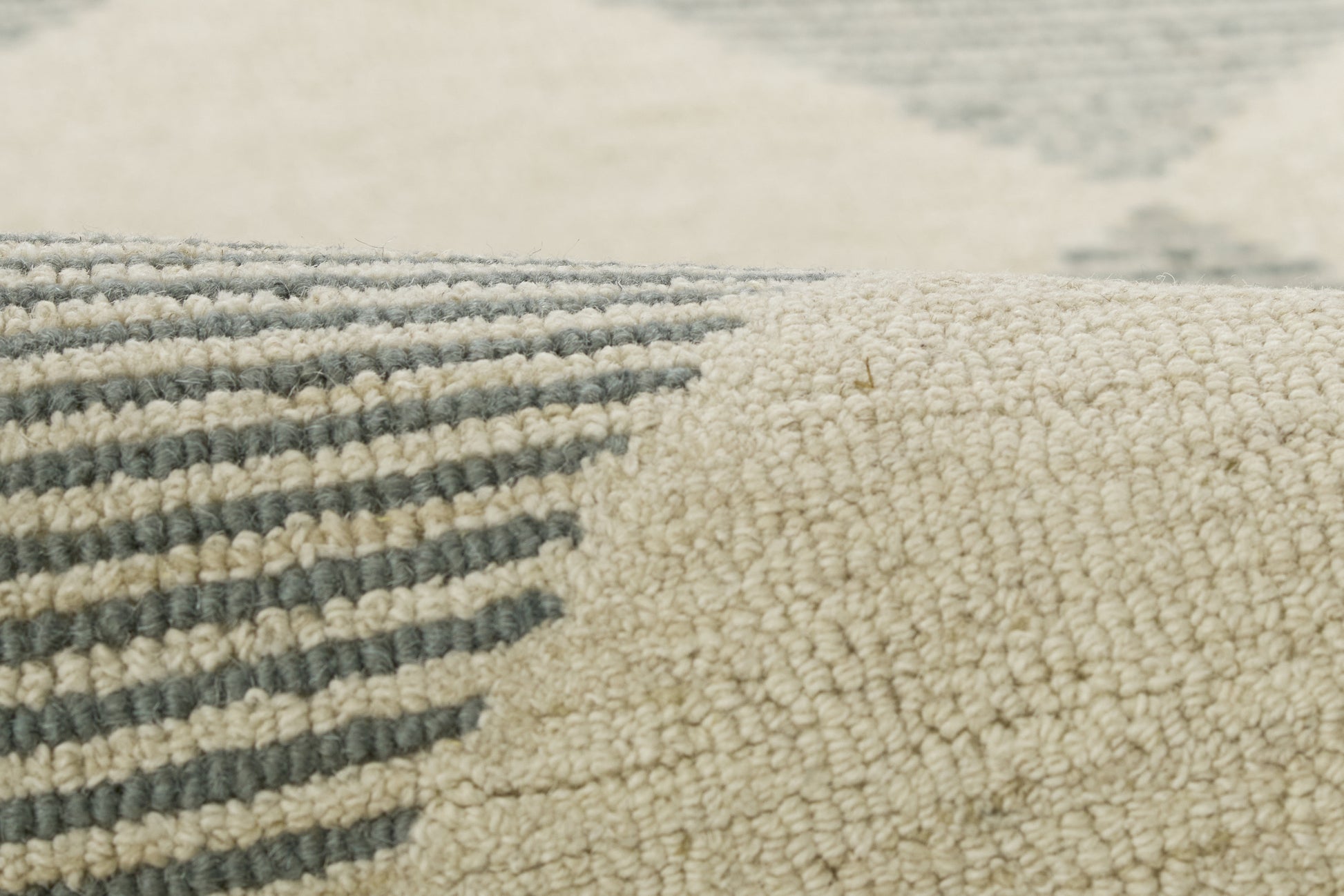 Close-up of a cream and blue-gray geometric rug with striped pattern and soft looped pile.