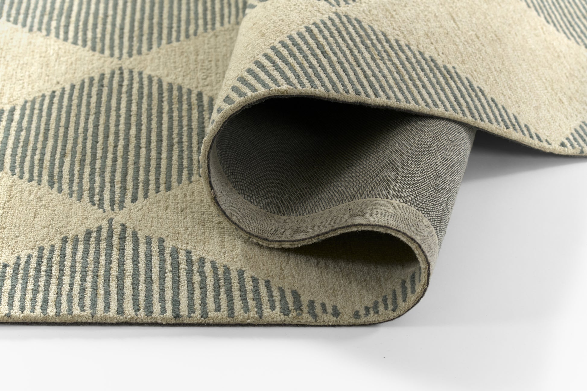 Beige flat-weave area rug with blue diamond/stripe geometric pattern, partially rolled to show underside.