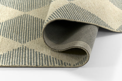 Beige flat-weave area rug with blue diamond/stripe geometric pattern, partially rolled to show underside.