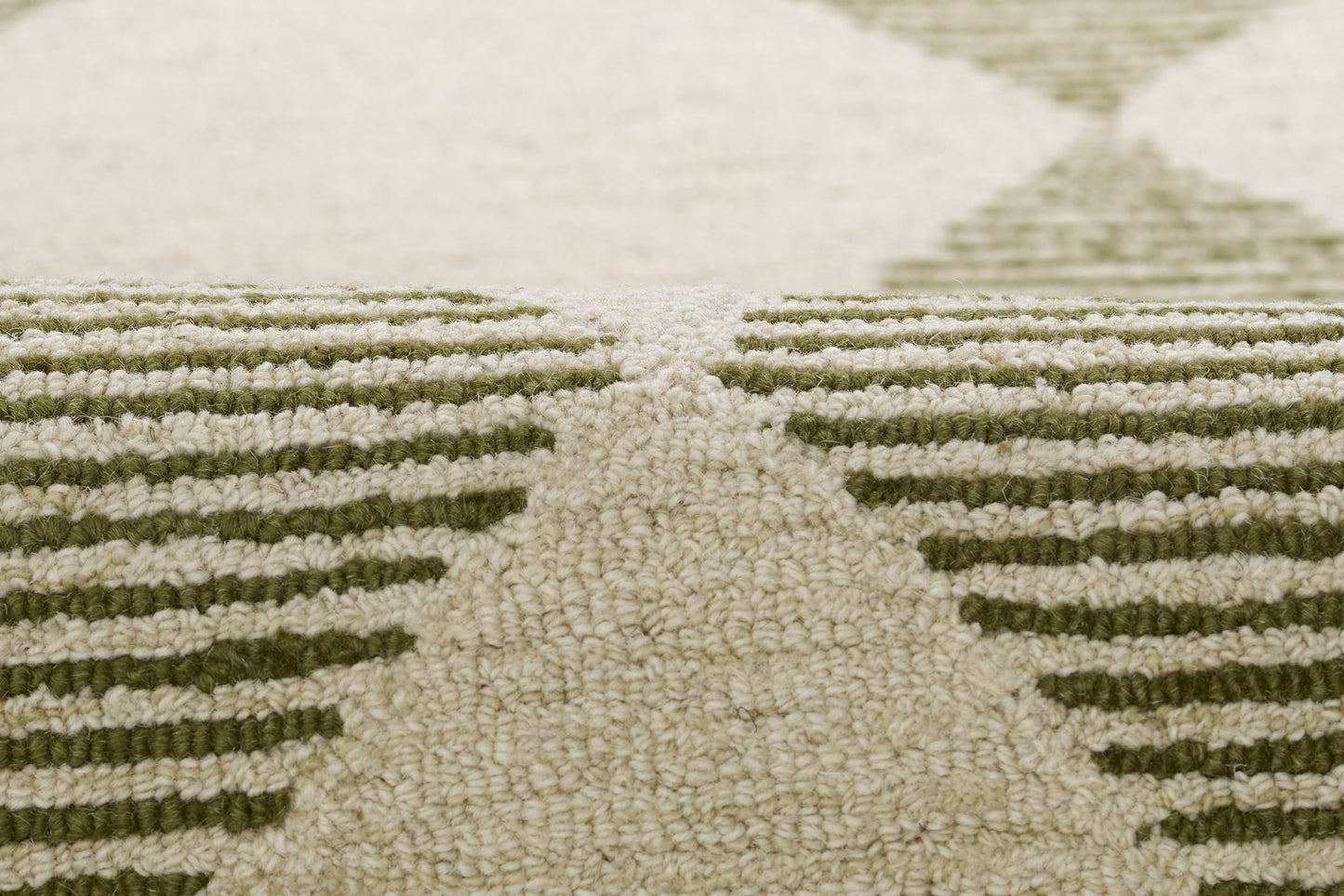 Close-up of beige rug with olive-green geometric chevron pattern and plush textured pile.