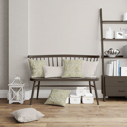 Dark brown wooden spindle-back bench with sage-green patterned and beige cushions beside a ladder bookshelf and boxes.