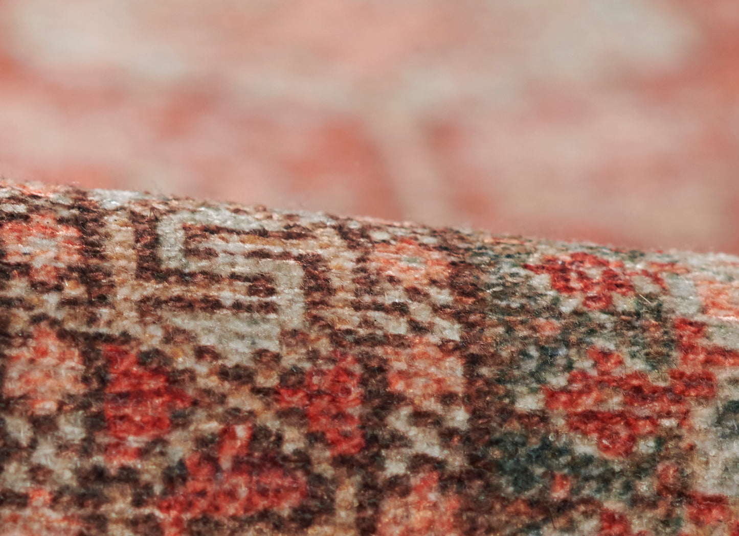 Close-up of red, cream and brown woven rug edge with soft pile and oriental-style pattern.