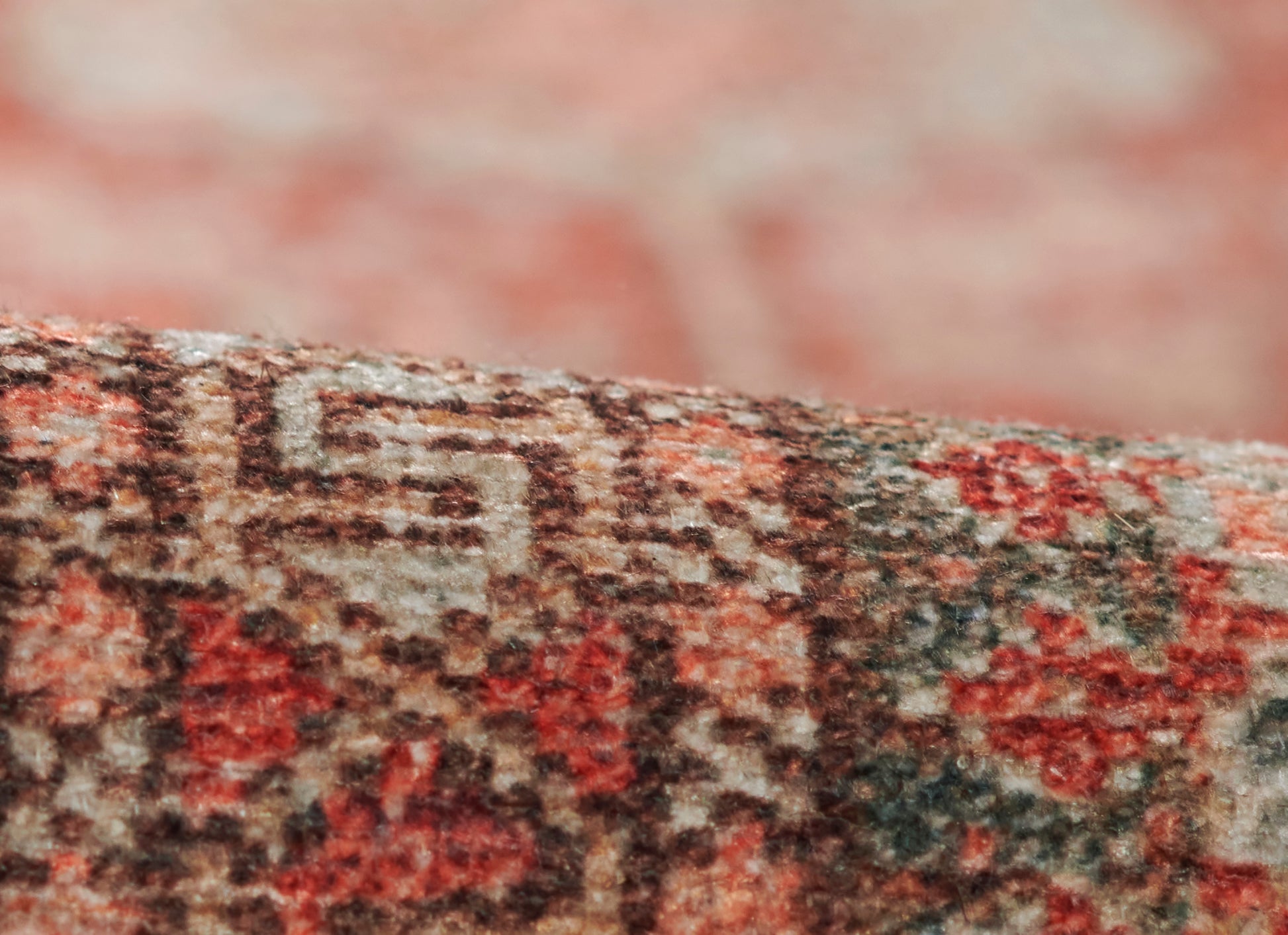 Close-up of a red, beige and brown Persian-style rug with an intricate woven pattern and plush texture.