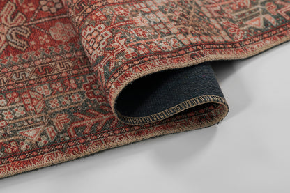 Persian-style red woven rug with beige and blue motifs; rolled edge shows beige binding and navy underside.