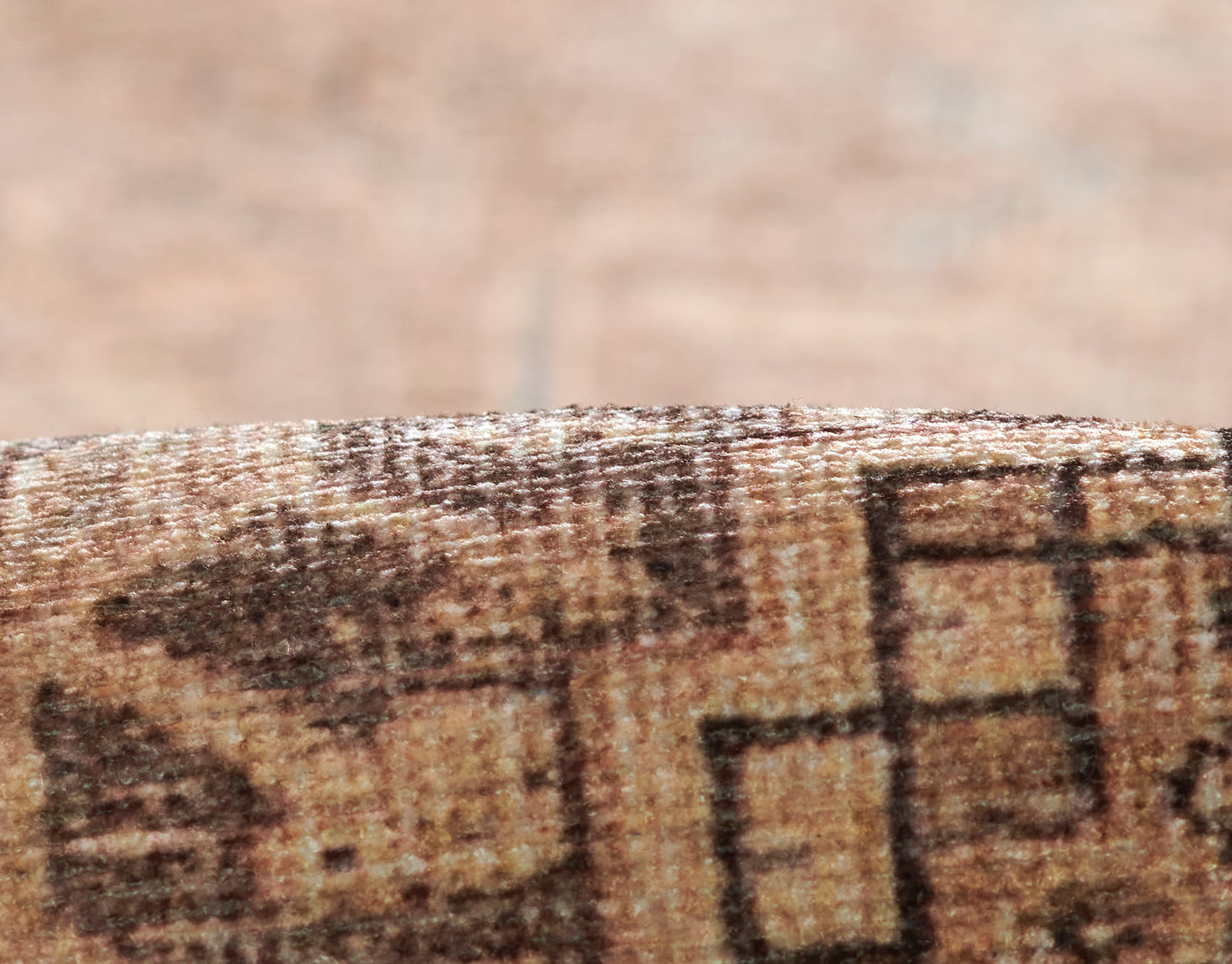 Close-up of brown geometric rug edge with tan and dark brown square blocks and plush woven texture.