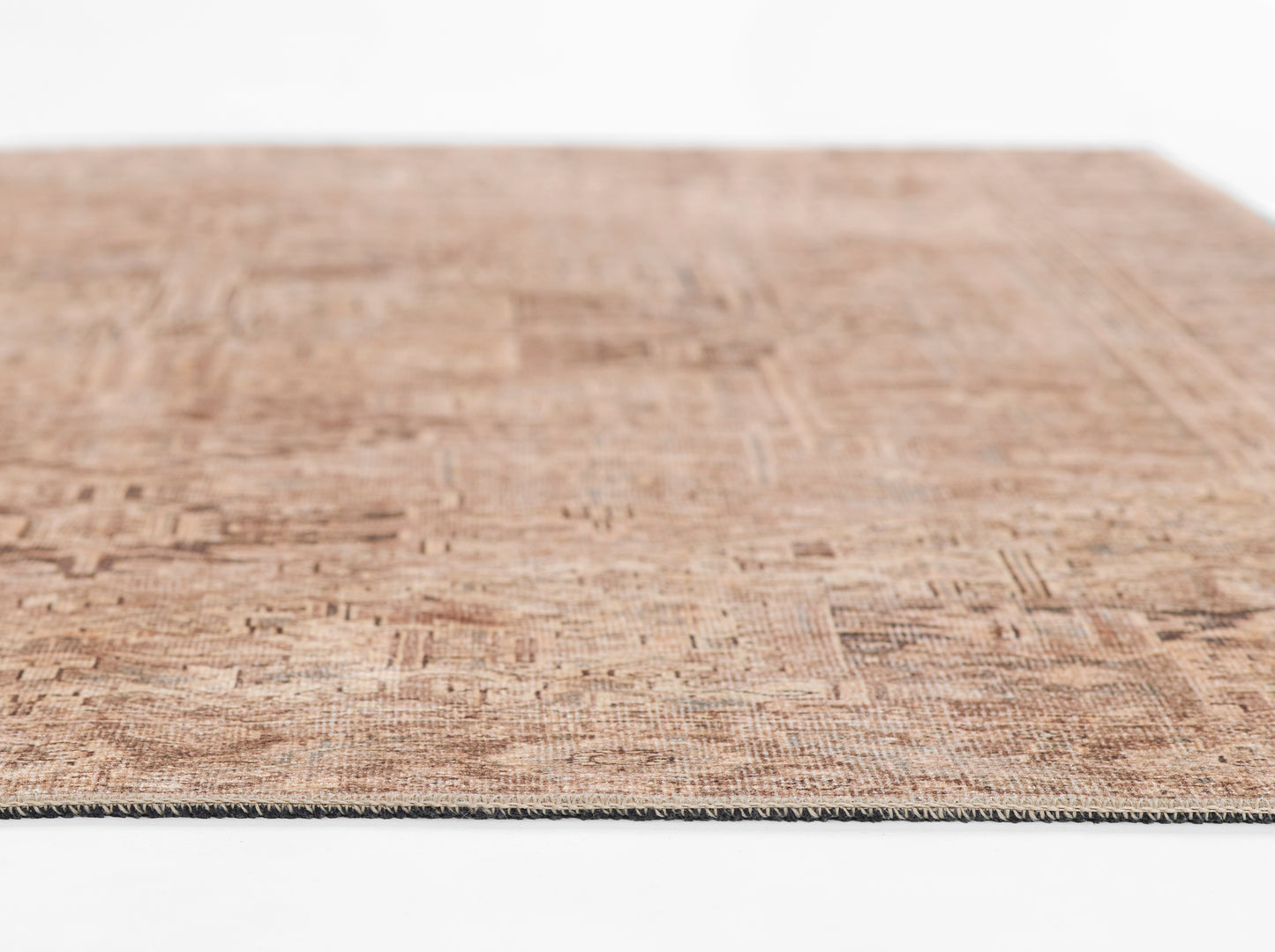 Brown woven rug with a textured abstract pattern in beige and brown tones, edge binding visible.