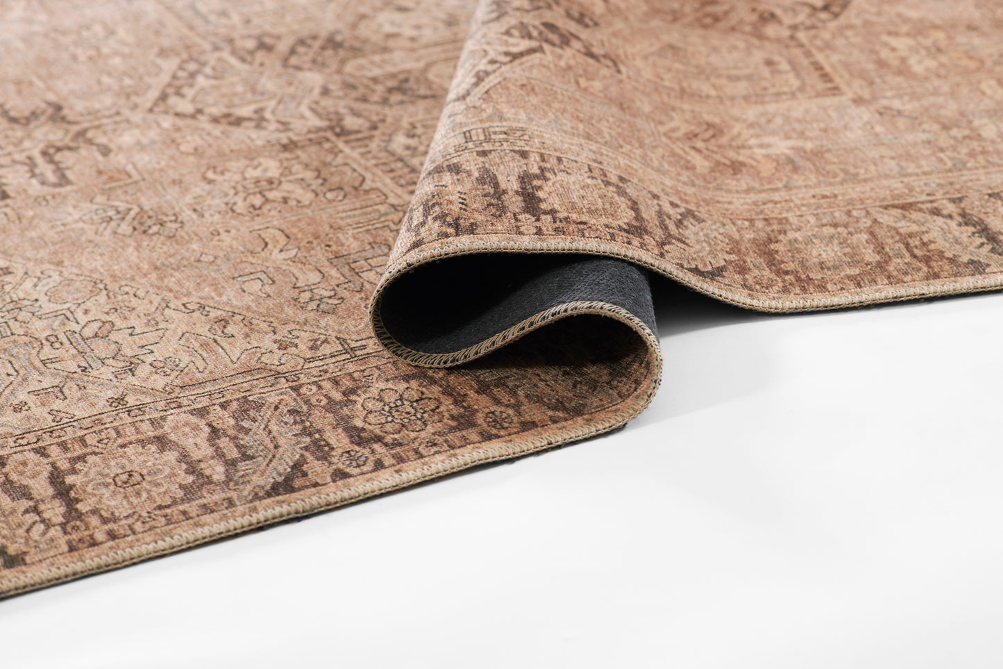 Brown oriental rug with antique floral motif, rolled edge showing beige fringe, warm woven texture, Persian-inspired decor.