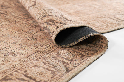 Brown oriental rug with antique tan patterns and geometric border; rolled corner reveals dark underside.