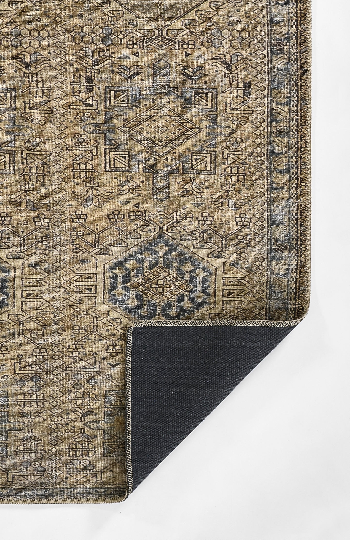 Beige-blue oriental area rug with geometric diamond medallions and ornate border; corner folded to show dark navy underside.