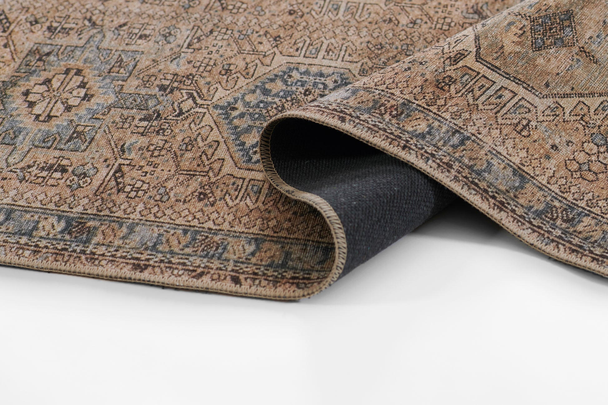Persian-style oriental rug with warm brown tones, blue border and intricate motifs, edge curled to reveal navy underside.