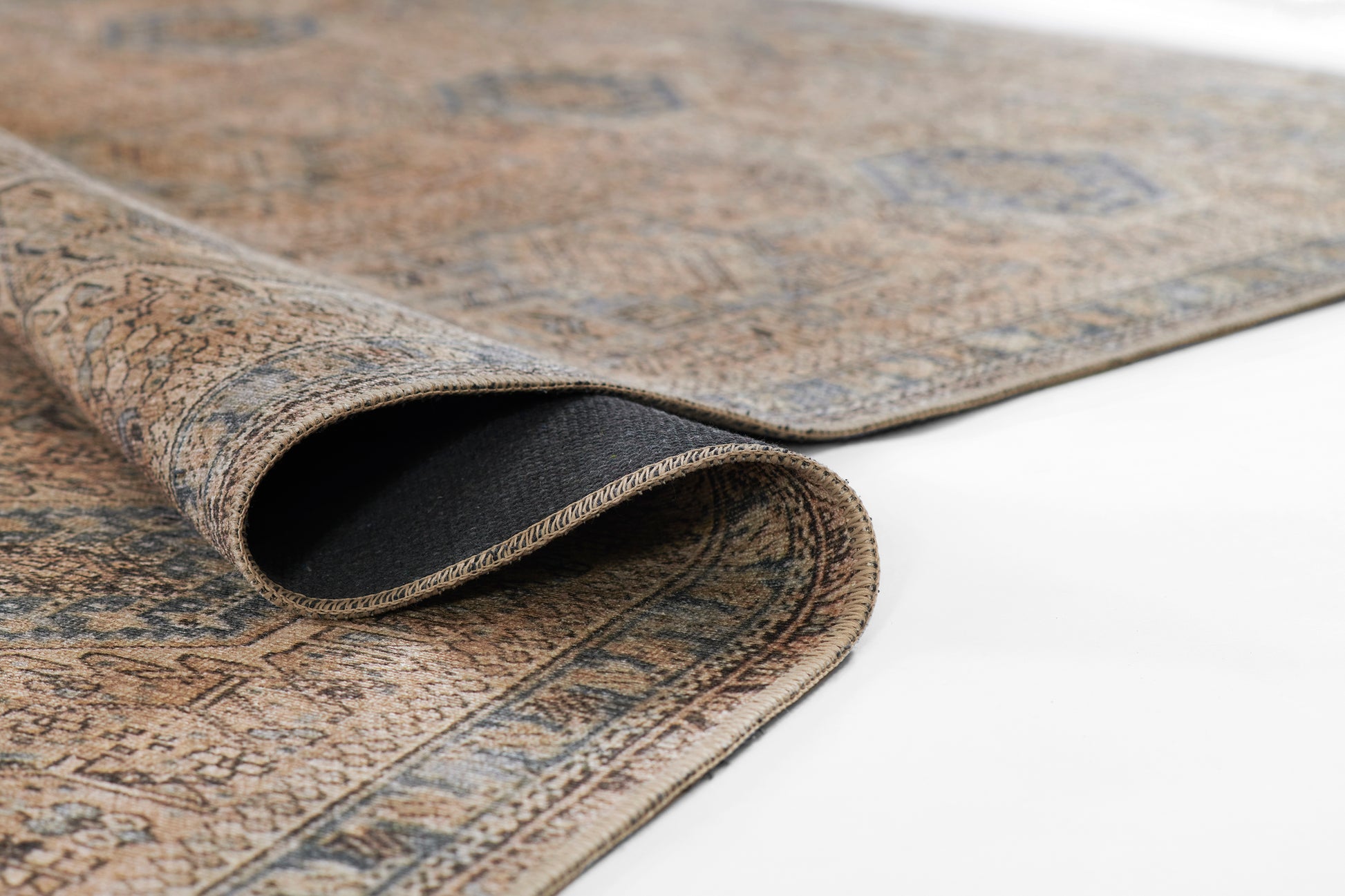 Brown and blue oriental rug with floral pattern, woven texture, rolled edge revealing black backing.