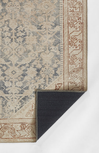 Beige and blue ornamental area rug with floral medallion motif, rust border; folded navy reverse shows weave.