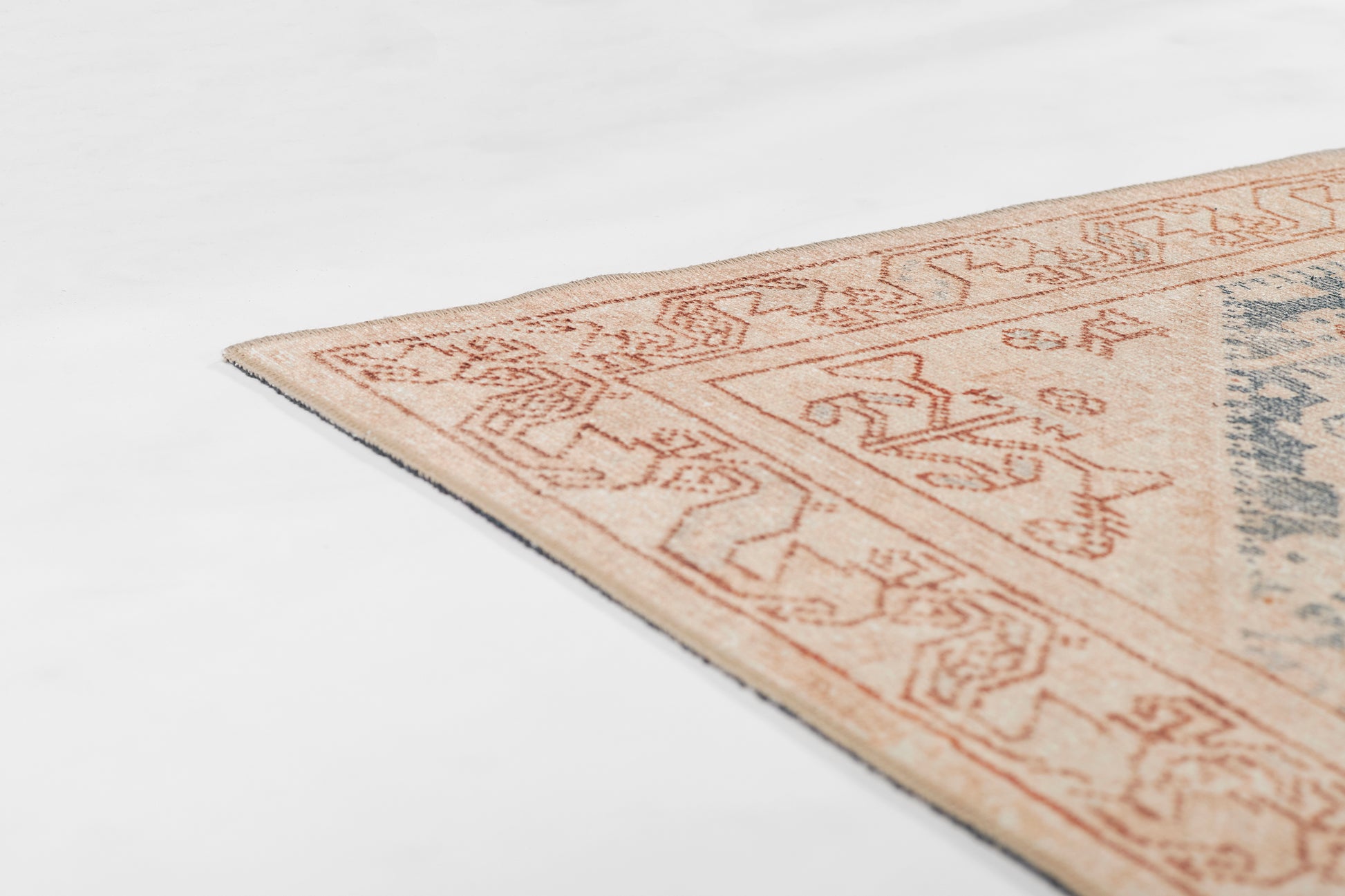 Corner of a blue runner rug with an orange geometric border and a muted blue-gray center.