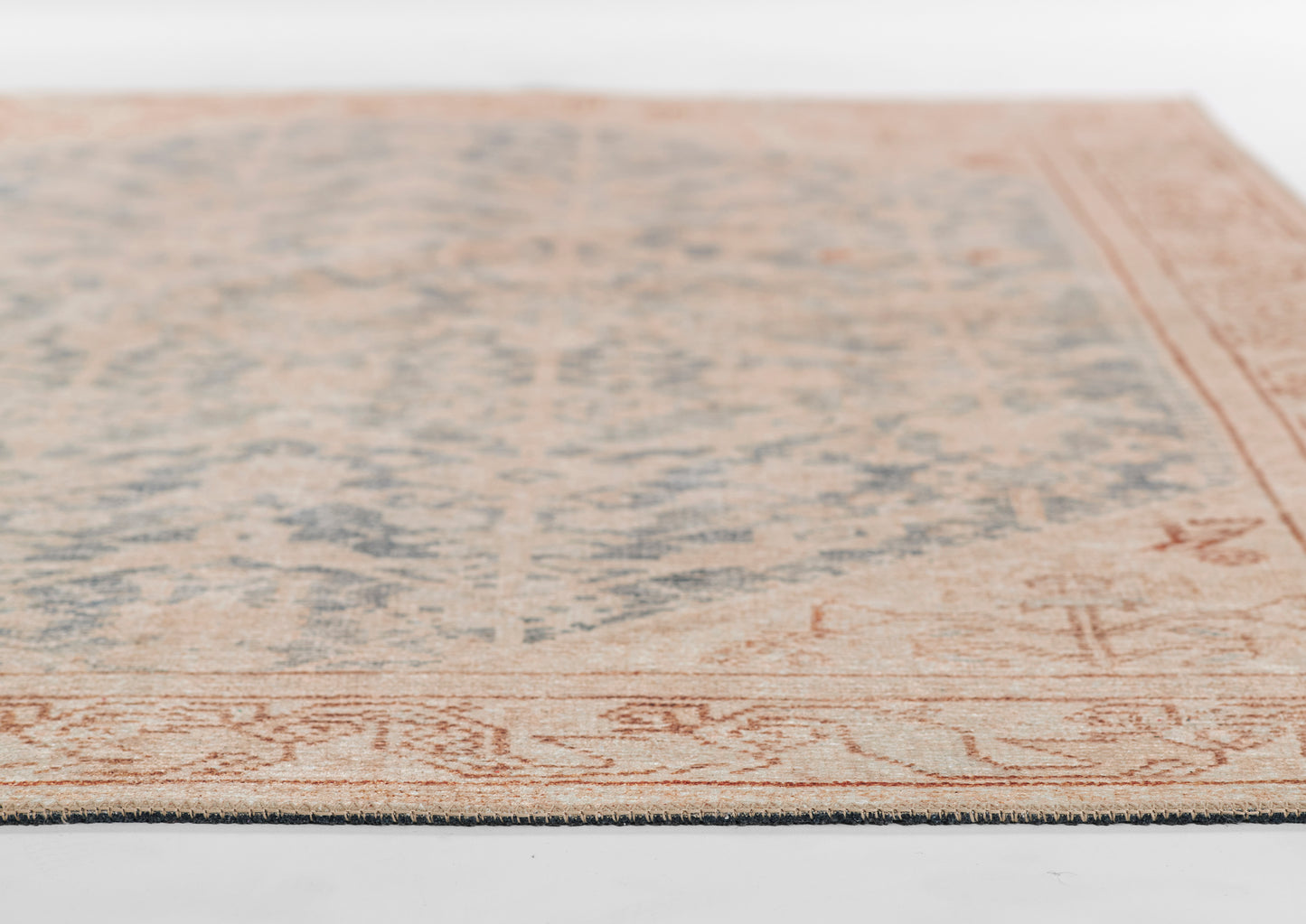 Rectangular vintage-style rug with pale blue distressed center and warm peach border.