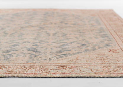 Rectangular rug with blue faded center and peach border, vintage oriental pattern.