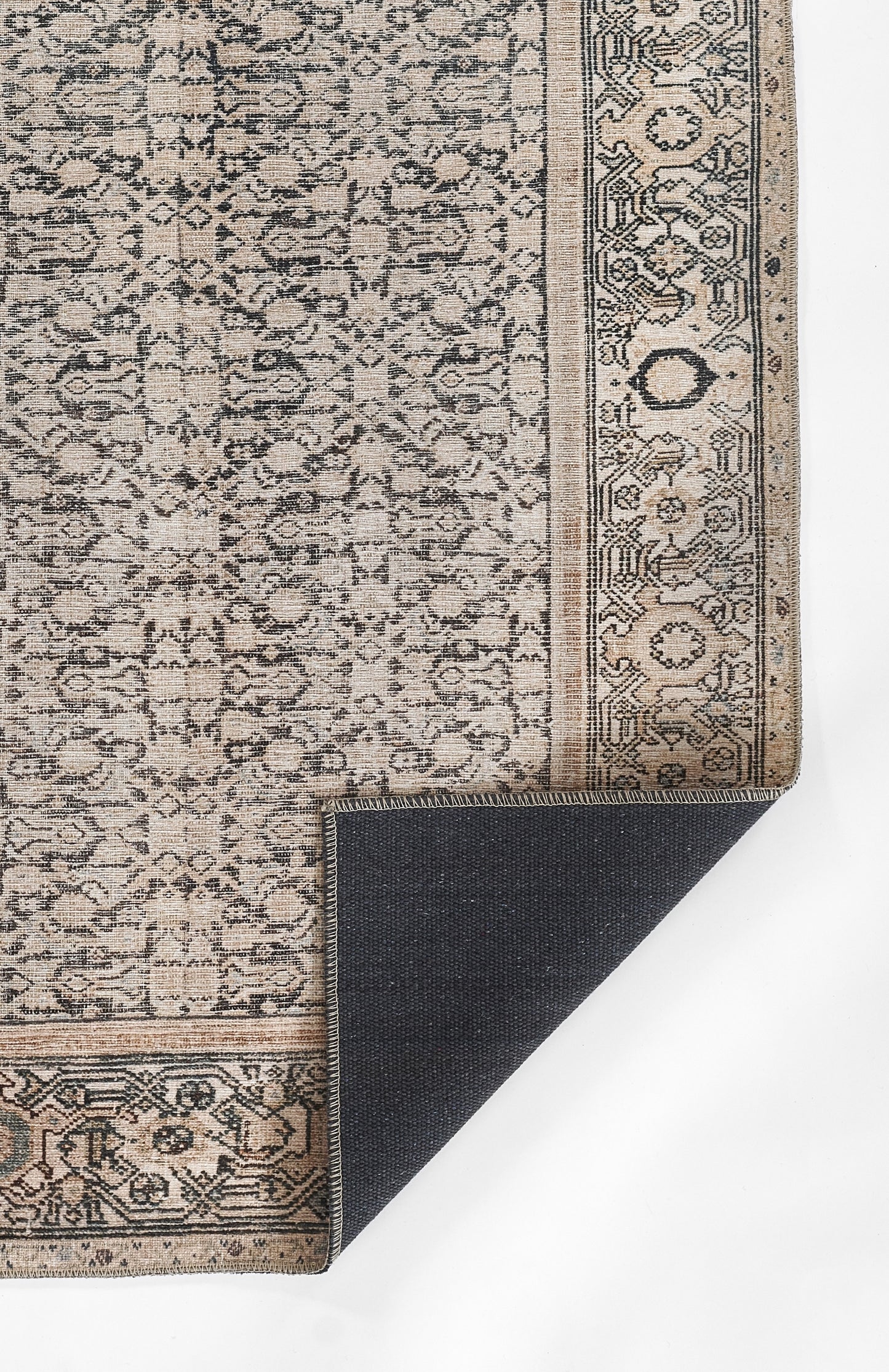 Beige oriental rug with dense dark blue floral arabesque pattern and bordered edge; corner lifted to reveal navy backing.