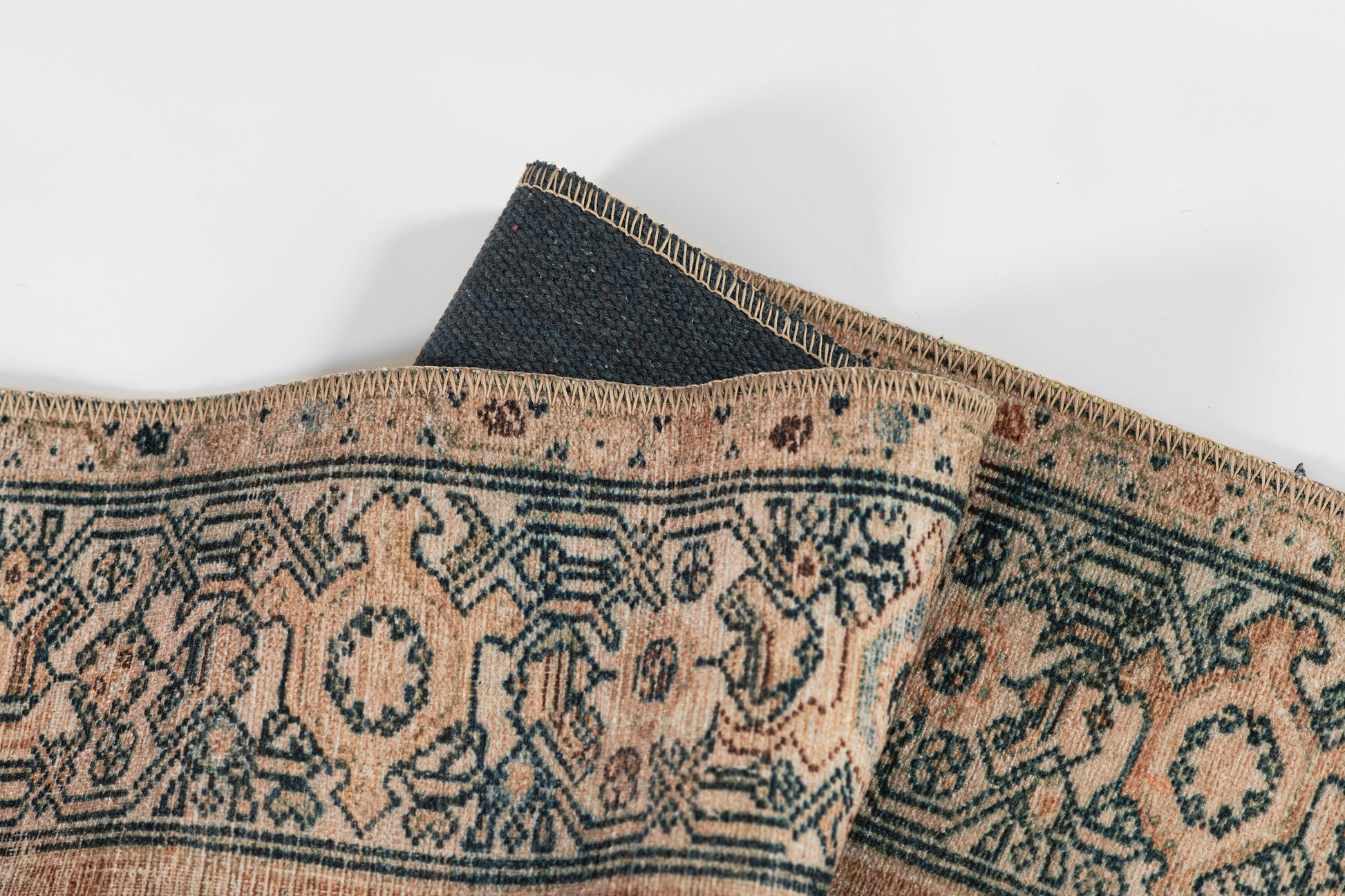 Peach-beige and navy woven oriental rug with geometric medallions, fringed edges, decorative home accent.