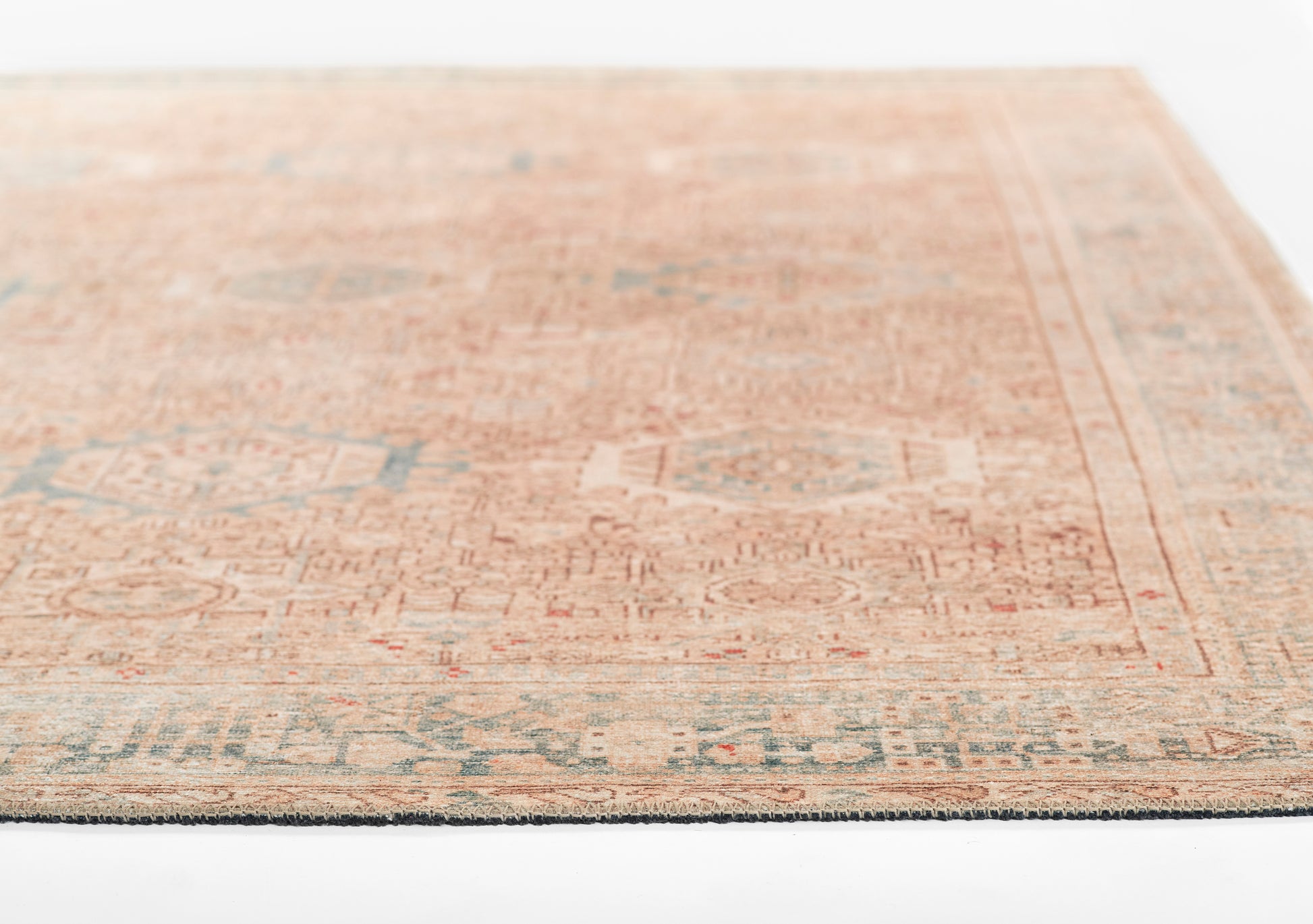 Muted peach oriental area rug with blue-gray accents, intricate geometric motifs and bordered fringe.