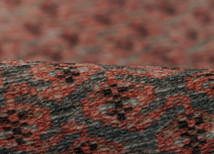 Close-up of a red and charcoal woven rug with a dense, textured pattern.
