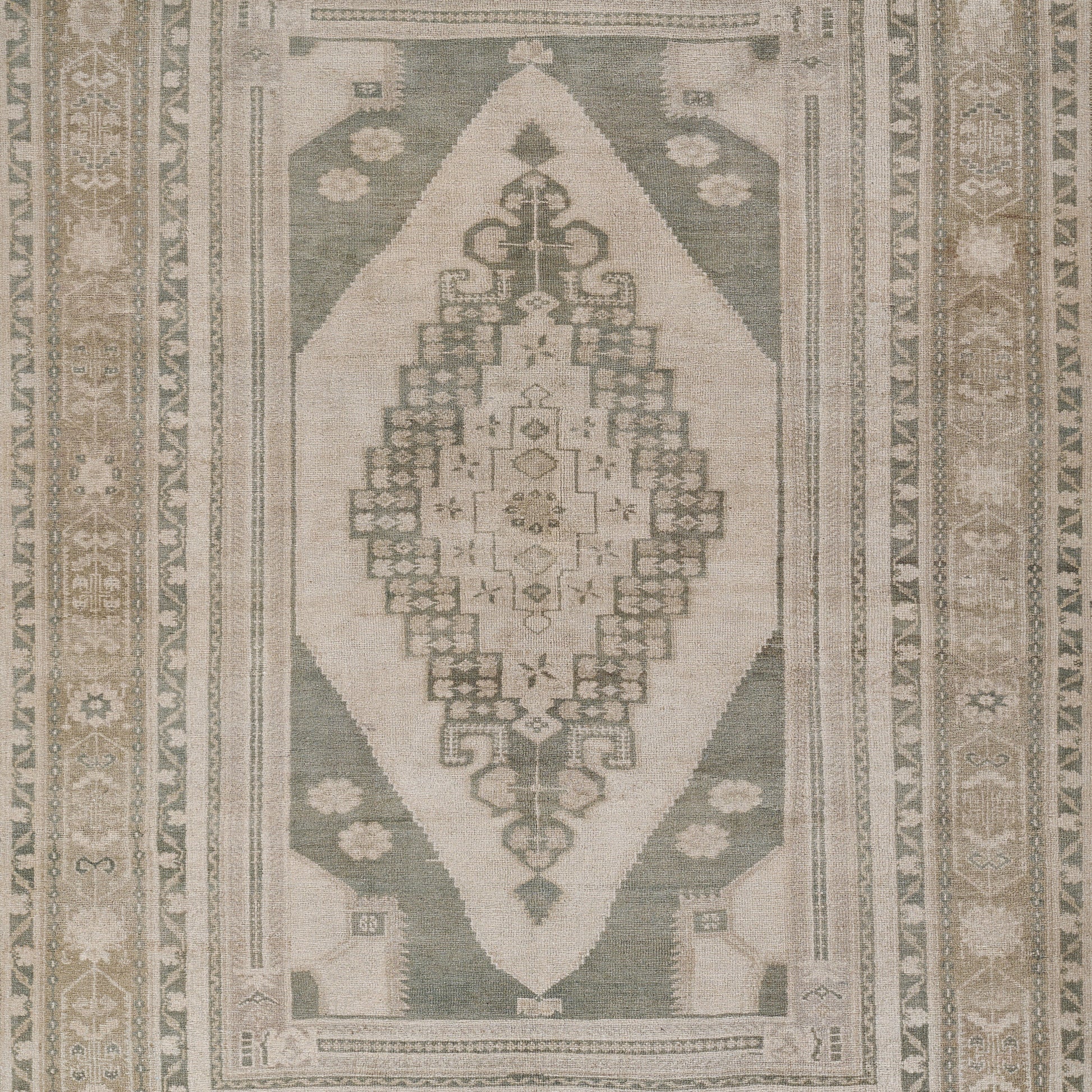 Rectangular green and beige oriental area rug with ivory central medallion and geometric border.