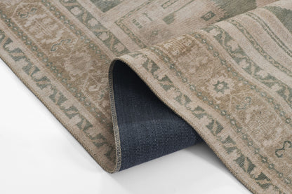 ARIANARI beige patterned runner rug with green motifs; folded corner shows dark navy backing, traditional oriental style.
