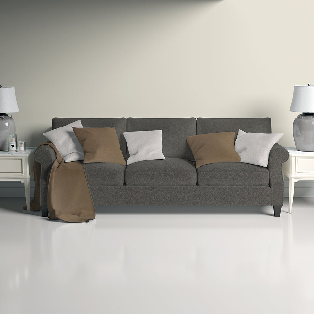 Nutmeg solid fabric three-seat sofa with tan and white cushions, tan throw, white end tables and lamps in a bright living room.