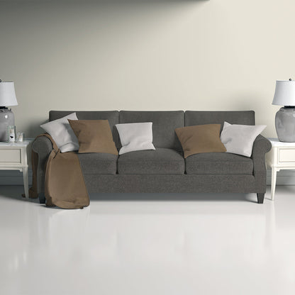 Nutmeg solid fabric three-seat sofa with tan and white cushions, tan throw, white end tables and lamps in a bright living room.