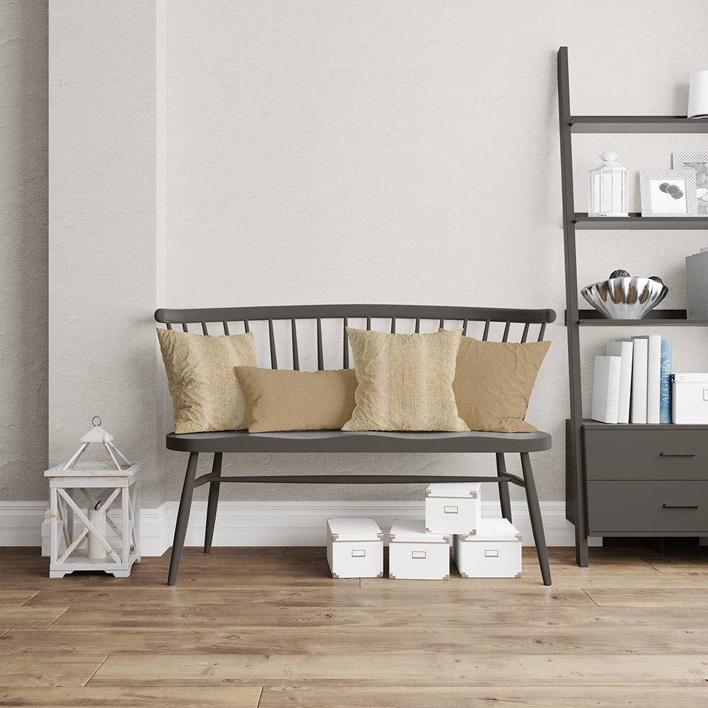 Dark metal-framed bench with beige cushions in a neutral living room, white lantern, storage boxes, and a black bookshelf.