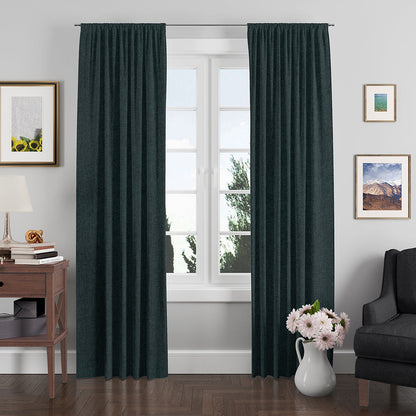 Dark teal pleated floor-length curtains framing a white window in a cozy living room, with a side table and vase of flowers.