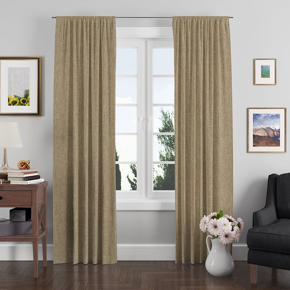Taupe linen solid fabric used for curtain panels framing a white window in a cozy living room with a lamp, books, a vase of flowers and a gray chair.