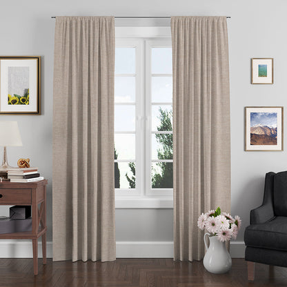 Beige textured floor-length curtain fabric framing a window in a cozy living room with wooden floor, lamp, art, and a vase.