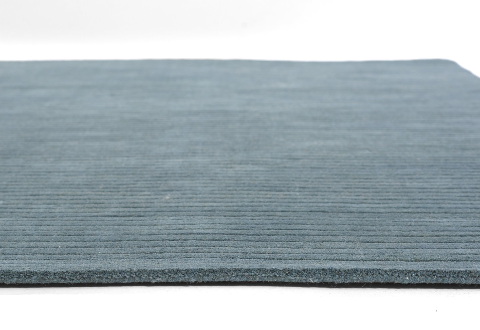 Blue ribbed rug with horizontal lines, low-pile texture, edge visible; casual, modern area rug.