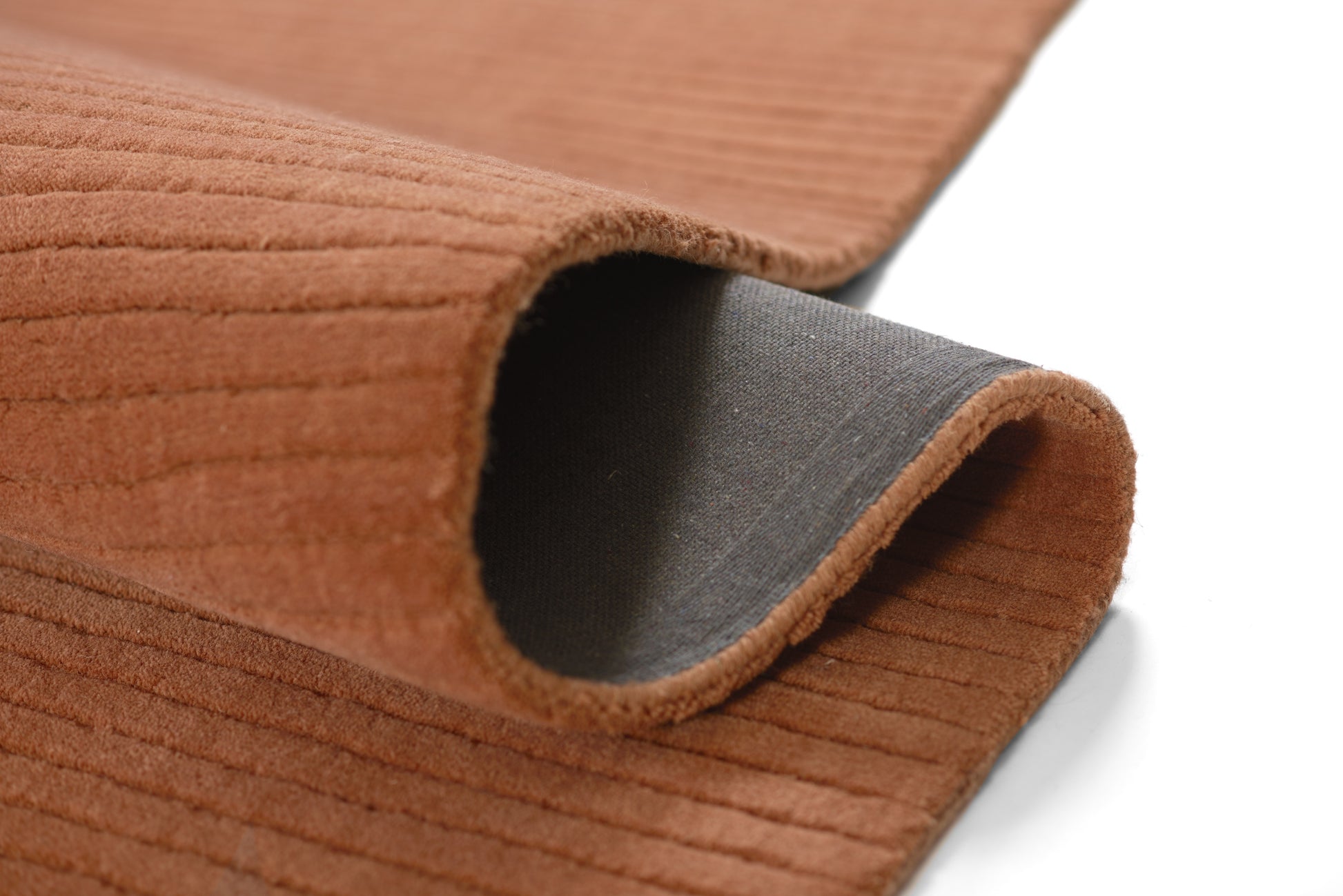 Brown suede-like fabric with horizontal ribbed texture, rolled edge revealing gray backing.