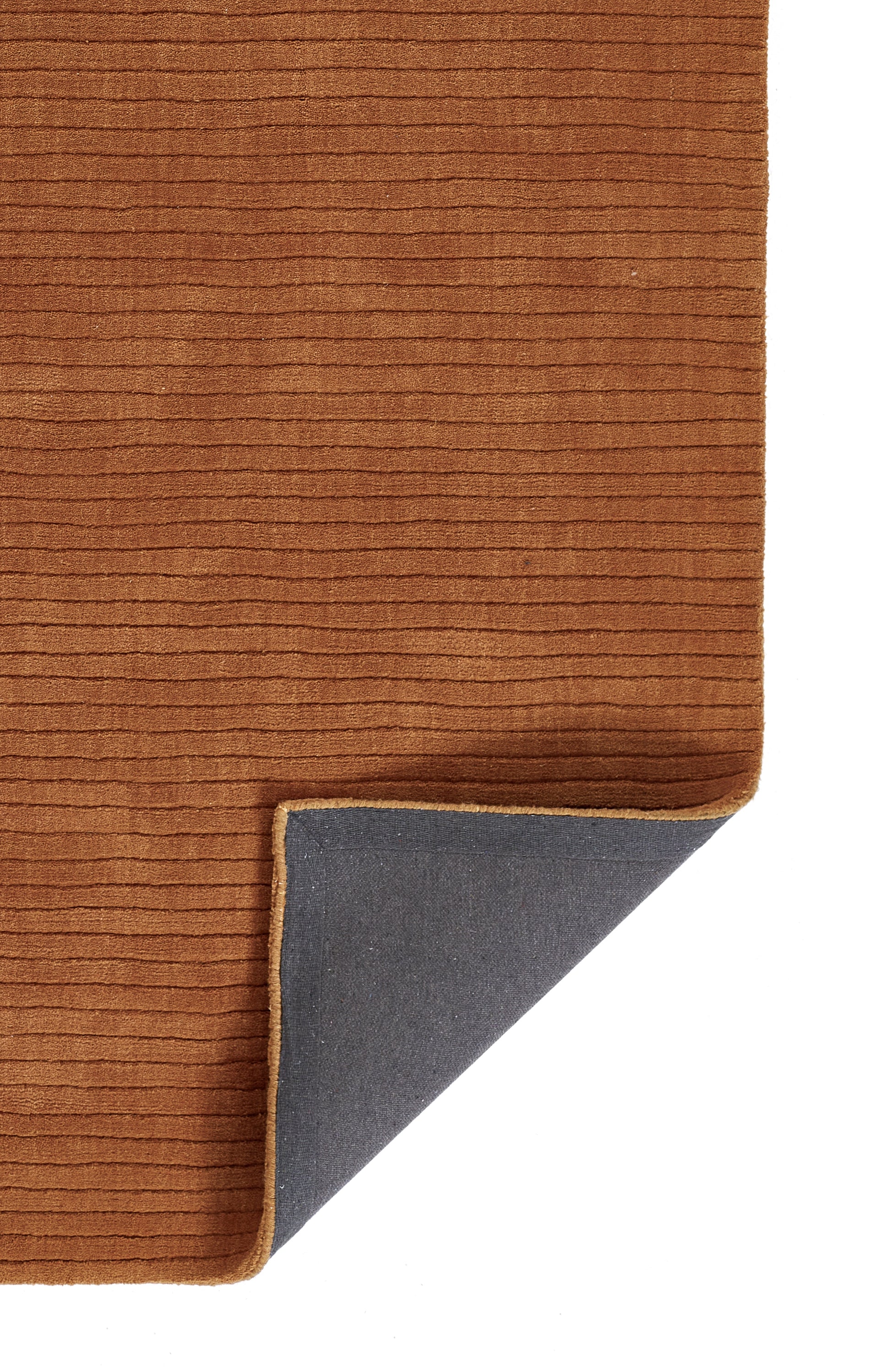 Brown corduroy rug with ribbed texture and tan edge; folded corner reveals gray non-slip backing.